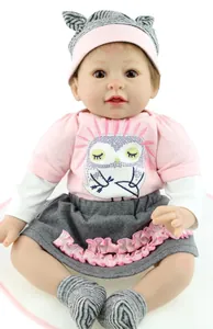 Gros plan d'un poupon réaliste portant un t-shirt rose hibou et un bonnet gris doux