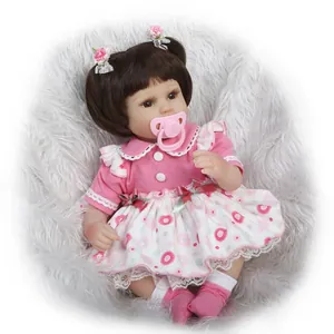 Close-up of lifelike baby doll with brown pigtails, lace dress and magnetic pacifier