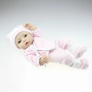 Lifelike reborn baby doll in pink striped outfit and hat lying on a neutral surface