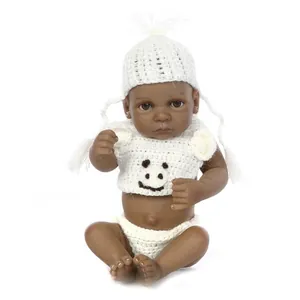 Detailed macro shot of a lifelike dark skin newborn doll in white knit baby clothes