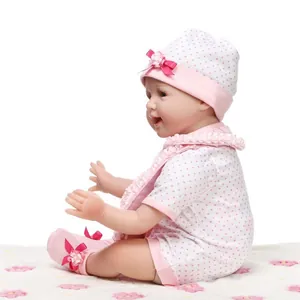 Dettaglio della bambola reborn realistica con vestito a pois rosa su coperta morbida
