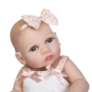 Close-up of realistic doll with brown eyes, long eyelashes and a pink polka dot headband