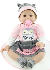 Détail d'une poupée Reborn réaliste avec haut rose hibou et bonnet en tricot gris