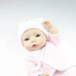 Realistic newborn baby doll in pink striped outfit with matching hat on gray background