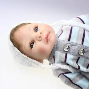 Realistic reborn baby doll with blue eyes and a white knitted hat in a soft close-up