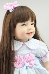 Detailed close-up of a lifelike reborn baby doll with long brown hair and pink floral dress