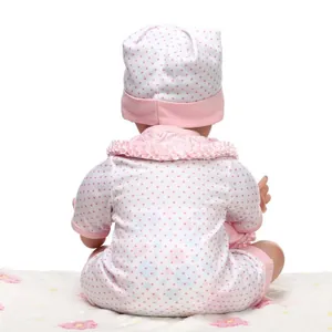 Vista posteriore di una bambola reborn realistica con tutina a pois rosa e cappello