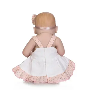 Rear view of a mini reborn baby doll wearing a pink polka dot dress and a matching headband