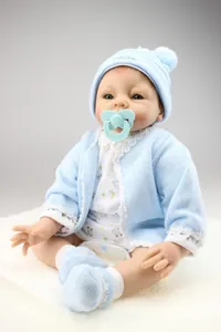 Detailed view of handmade silicone reborn baby doll in blue knit outfit and accessories