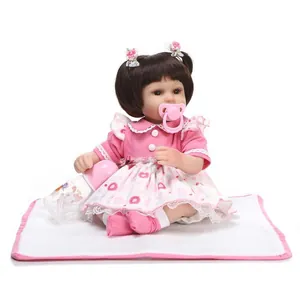 Close-up of realistic reborn baby doll with pink floral outfit, pacifier, and milk bottle