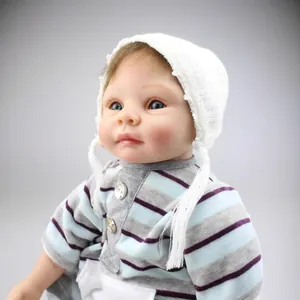 Lifelike reborn baby doll in striped outfit and white lace crochet hat with blue eyes