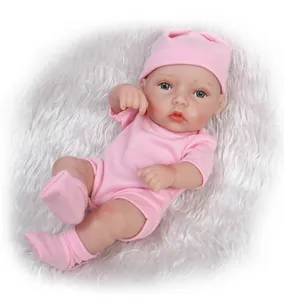 Realistic mini reborn baby doll in pink knit hat and matching outfit on plush rug