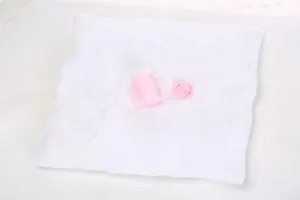 Detailed view of pink doll feeding bottle and pacifier on white plush towel