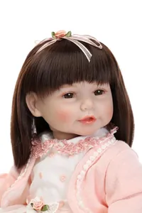 Close-up of cute reborn doll with brown hair, pink bow, and delicate facial details