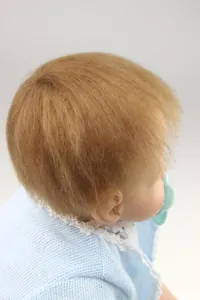 Close-up of realistic reborn doll showing fine rooted hair and blue pacifier detail