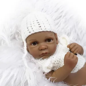 Mini creative dark skin reborn baby doll in white knit hat on plush background