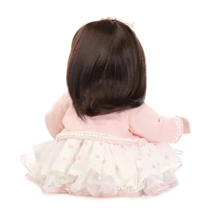Lifelike girl doll with long brown hair in pink cardigan and white polka dot tutu dress