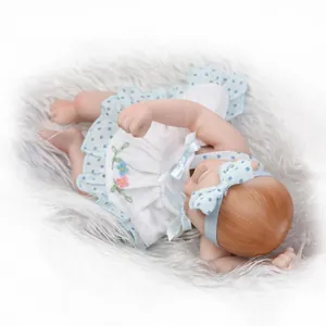 Detail view of mini reborn doll in white floral dress sleeping on grey plush rug