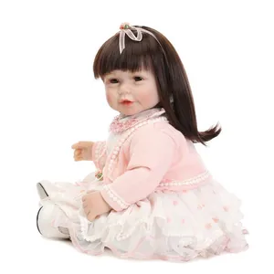 Realistic reborn girl doll with long brown hair in pink knit cardigan and lace dress