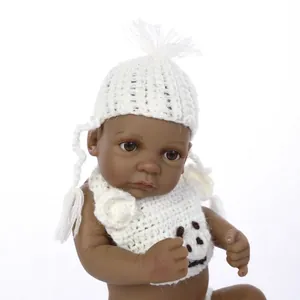 Miniature reborn baby doll with deep skin tone in handmade white knitted bear outfit