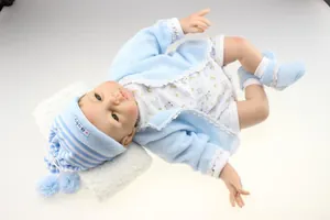 Close-up of lifelike reborn baby doll in light blue knitwear and pom-pom baby hat