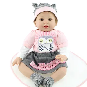 Poupée bébé Reborn réaliste avec tenue de hibou et bonnet rayé sur tapis rose
