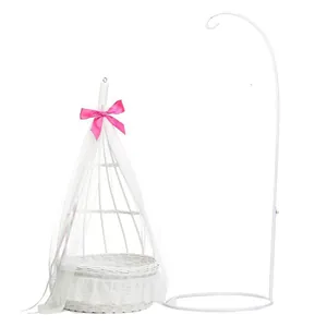 Detail of white woven baby doll bassinet with sheer canopy and pink satin bow decor