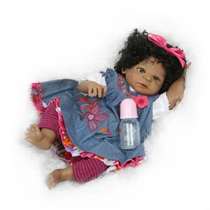 Realistische Reborn-Babypuppe mit schwarzen Locken und floralem Jeanskleid auf Plüsch