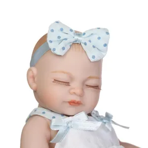 Detailed close-up of a realistic sleeping reborn baby doll with blue polka dot headband