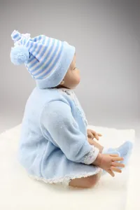 Detailed side view of a lifelike reborn baby doll in a blue knit outfit and pom-pom hat