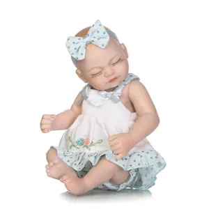 Detailed close-up of a sleeping mini reborn baby doll with floral dress and bow headband