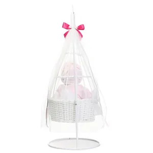 Detailed view of a white wicker baby cradle with metal stand and soft pink bow accents