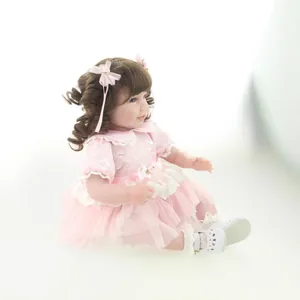 Lifelike 20-inch reborn girl doll in pink floral dress with brown curly hair and bows