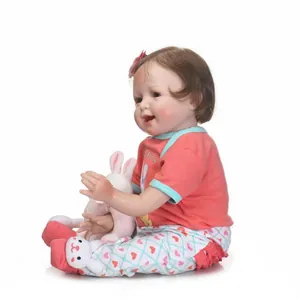 Realistic reborn baby doll with brown hair, pink floral headband and plush rabbit toy