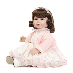 Close-up of lifelike baby doll in pink knit cardigan and white polka dot lace dress