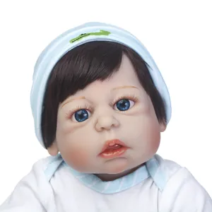Realistische Reborn-Babypuppe mit blauen Augen und blauer Strickmütze auf weißem Grund