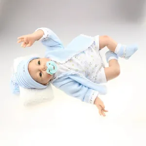 Lifelike reborn baby doll in blue knit cardigan and hat resting on white plush cushion