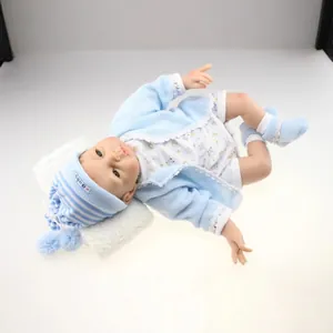 Lifelike reborn baby doll in light blue knit outfit resting on white soft cushion