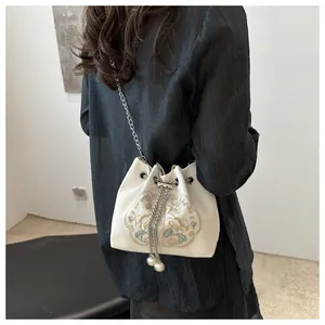 Détail de la broderie florale et cordon perle sur le sac seau blanc cassé avec chaîne
