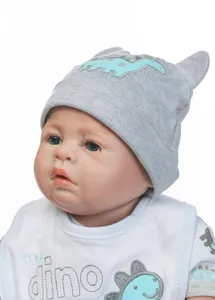 Detail einer Neugeborenen-Puppe mit grauer Dino-Strickmütze und passendem Lätzchen