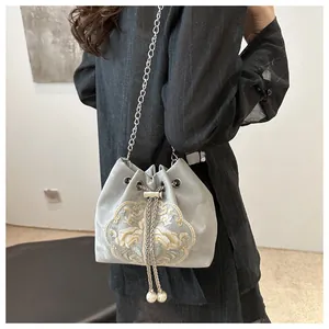 Détail de broderie florale chinoise sur un sac seau gris avec des glands en perles