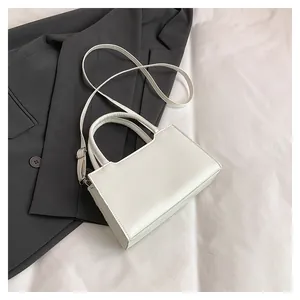 Overhead shot of minimalist beige faux leather handbag on a blazer for a chic office look
