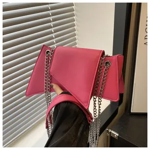Detalle de bolso geométrico rosa fucsia con cadena plateada y correa de cuero