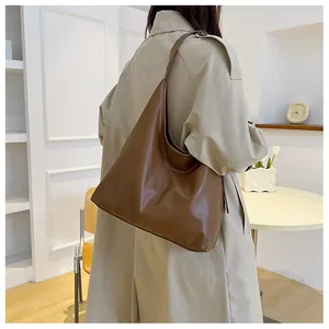 Brown matte leather hobo tote bag shown on a model in a cozy indoor cafe setting