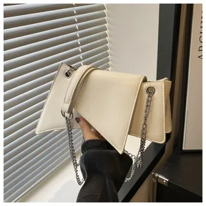 Detalle del bolso geométrico blanco roto con cadena plateada y cuero de textura mate