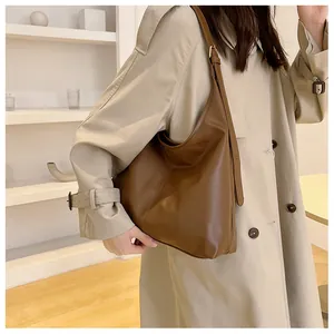 Brown faux leather hobo shoulder bag with adjustable strap and stitching detail on a model