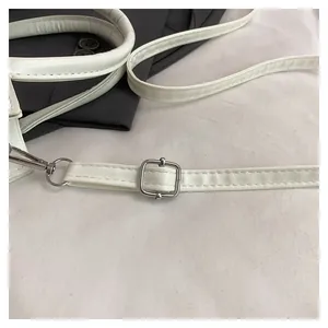 Detailed close-up of white leather shoulder strap with silver metal buckles and fine stitching