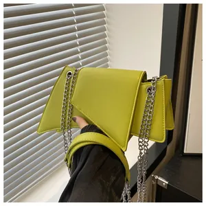 Detalle del bolso geométrico verde neón con forma asimétrica y cadena de metal plateada