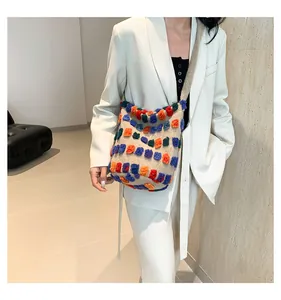 Détail du sac cabas au crochet à pompons colorés porté sur un blazer blanc