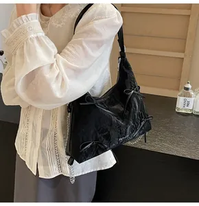 Détail du sac sous le bras noir plissé brillant avec noeud et chaîne en argent